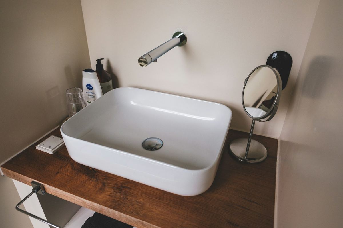 White countertop basin on a wooden vanity against neutral tiles