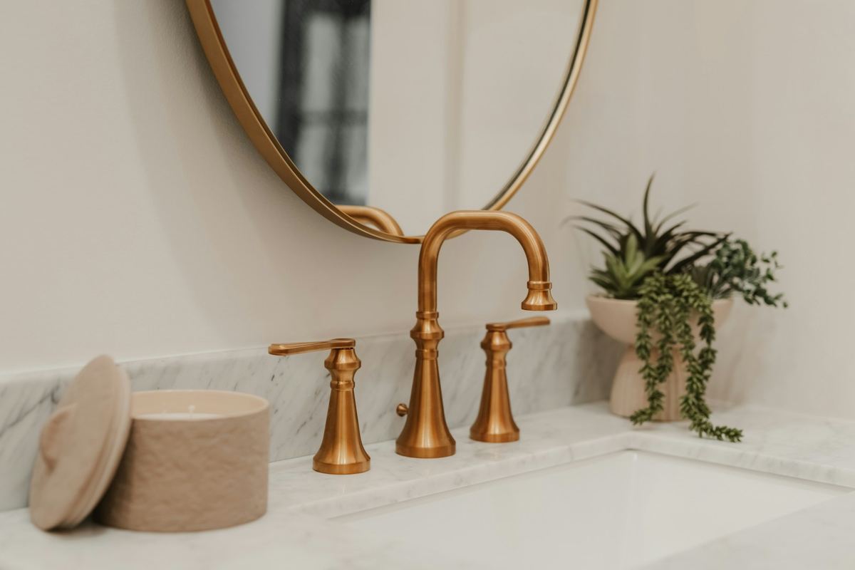 Pair of brass wall-mounted taps against a marble wall